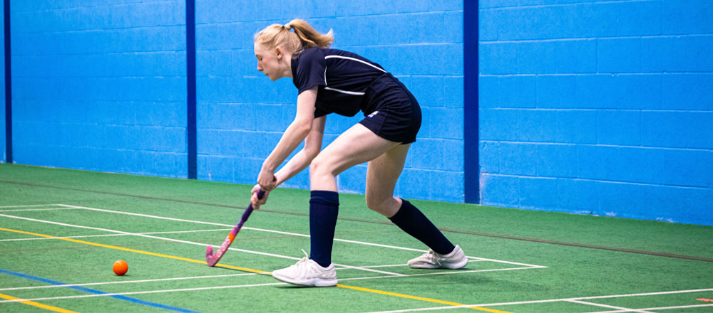 pupil playing hockey in the sports hall